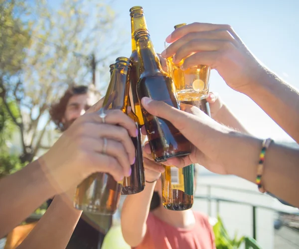 primer-plano-amigos-contentos-tintineando-botellas-vasos-cerveza-personas-diferentes-nacionalidades-levantando-botellas-riendo-celebrando-cumpleanos-fiesta-concepto-amistad-scaled